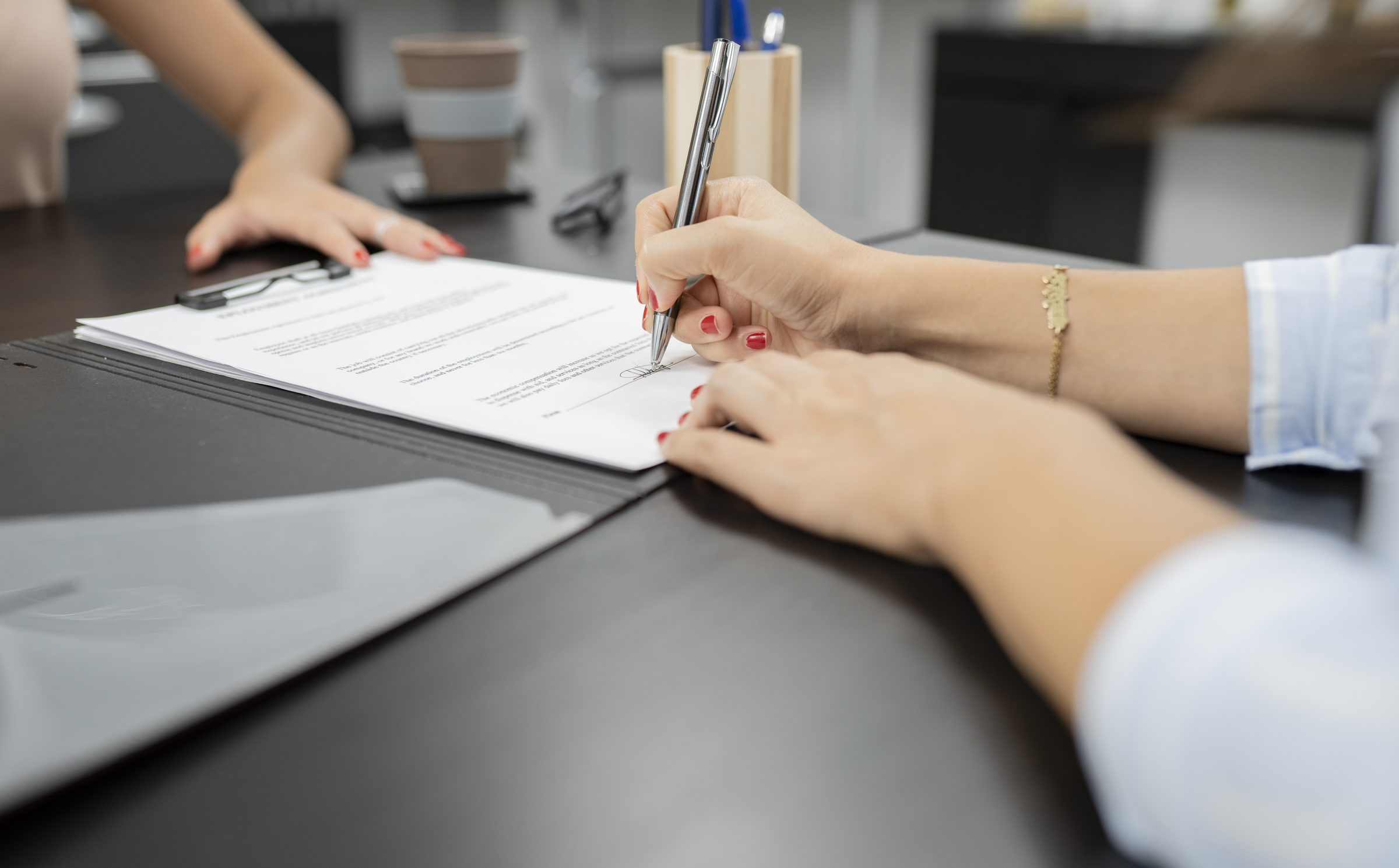 Mão assinando um contrato sobre uma mesa