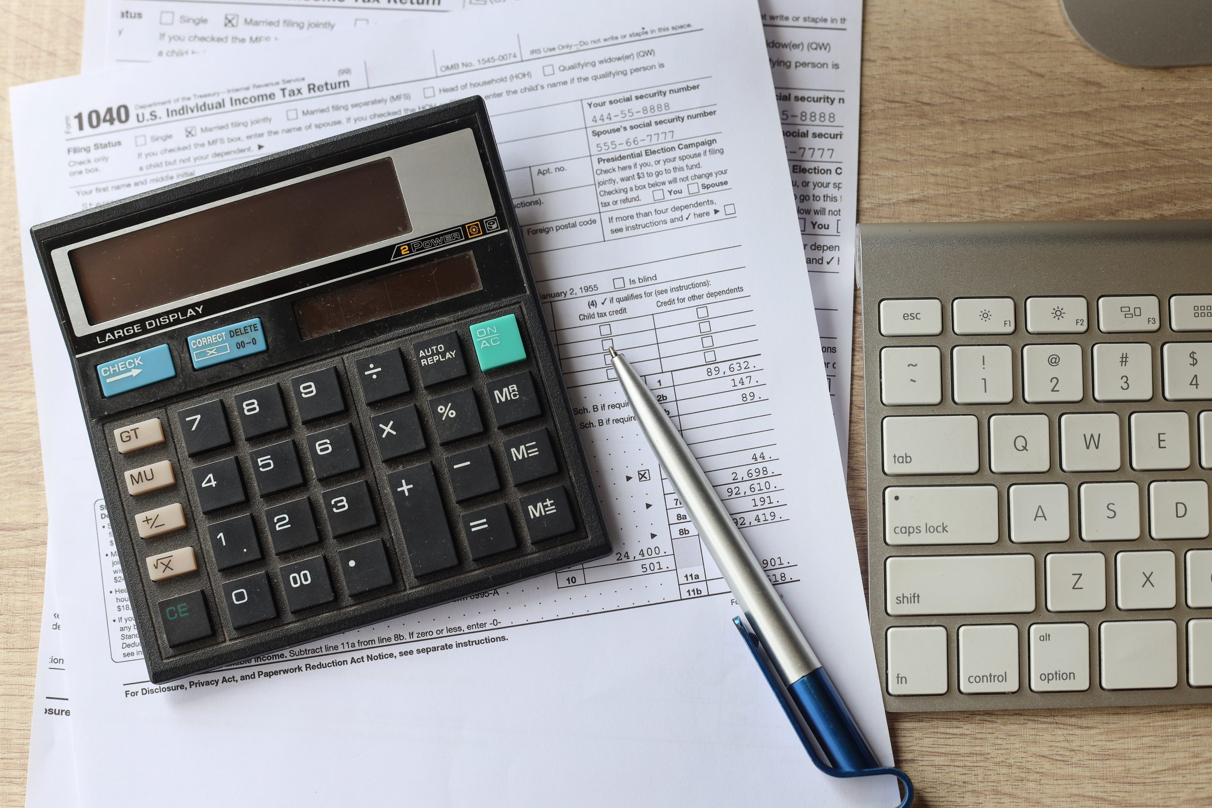 Calculadora, caneta e papéis de imposto sobre uma mesa